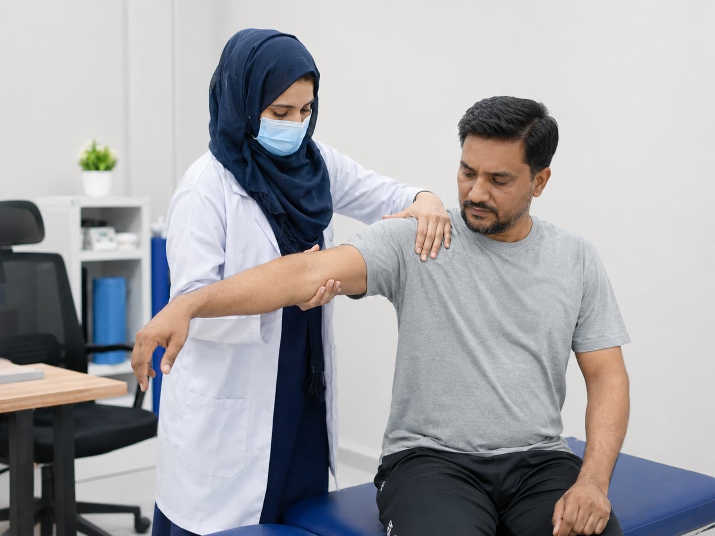 female physiotherapist helping a male patient with shoulder arm movement