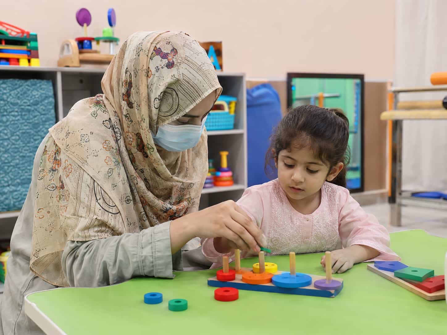 occupational therapist helping a young girl with a peg activity during occupational therapy