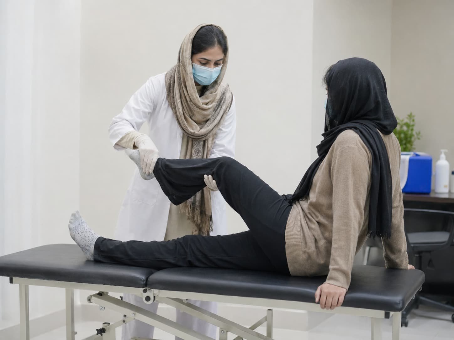 physiotherapist treating a female patient with leg mobility and raising exercises during sciatica treatment